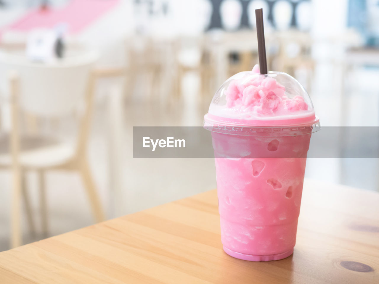 Cold milk smoothie drink in a plastic cup on a wooden table and has sunlight a beautiful background