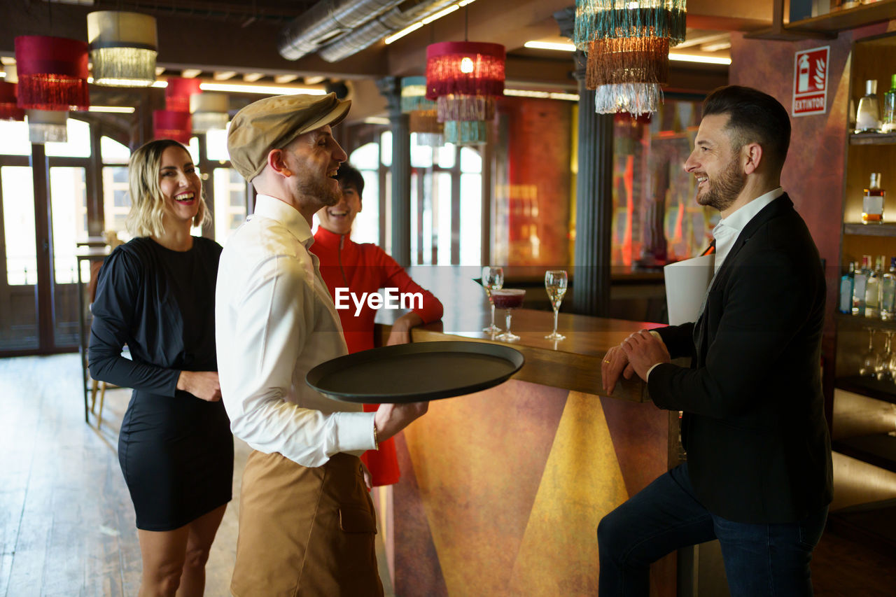 Smiling friends talking with bartender