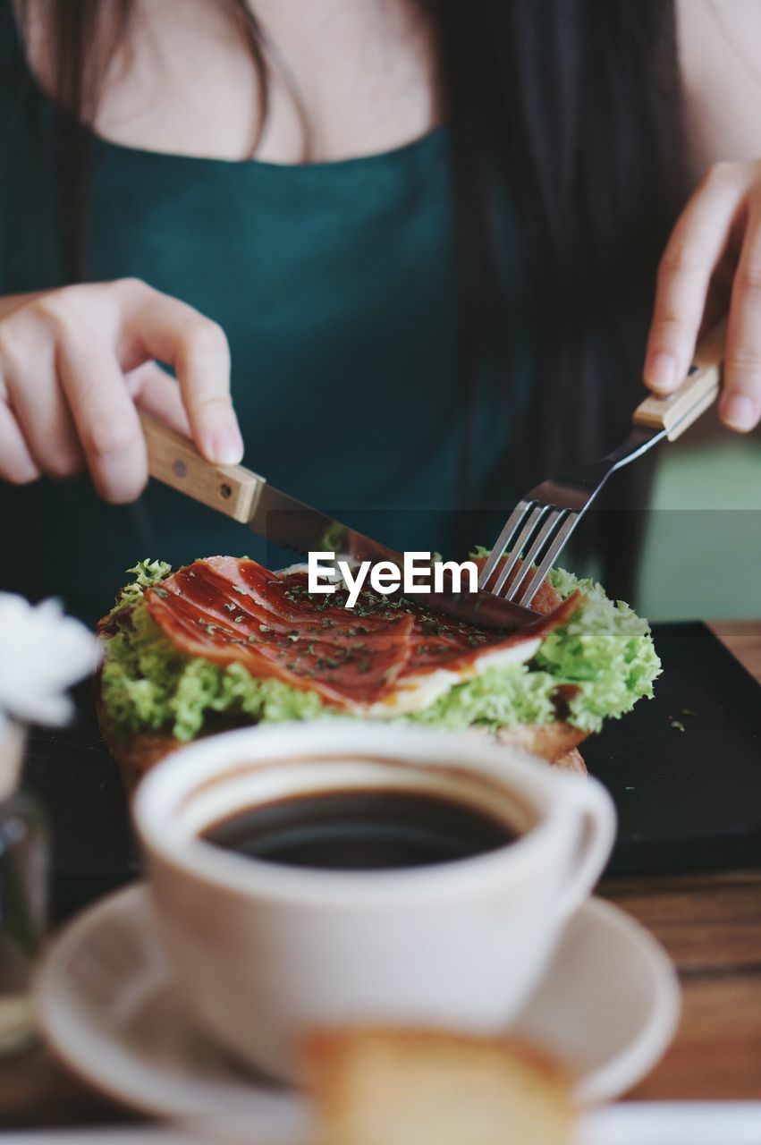 Midsection of woman using cutlery while cutting food