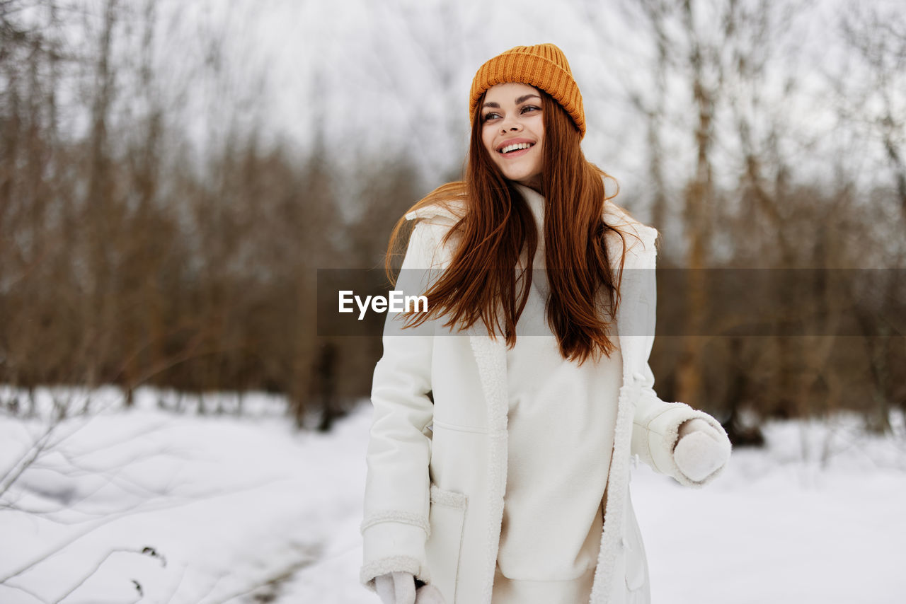 portrait of young woman standing on snow covered field