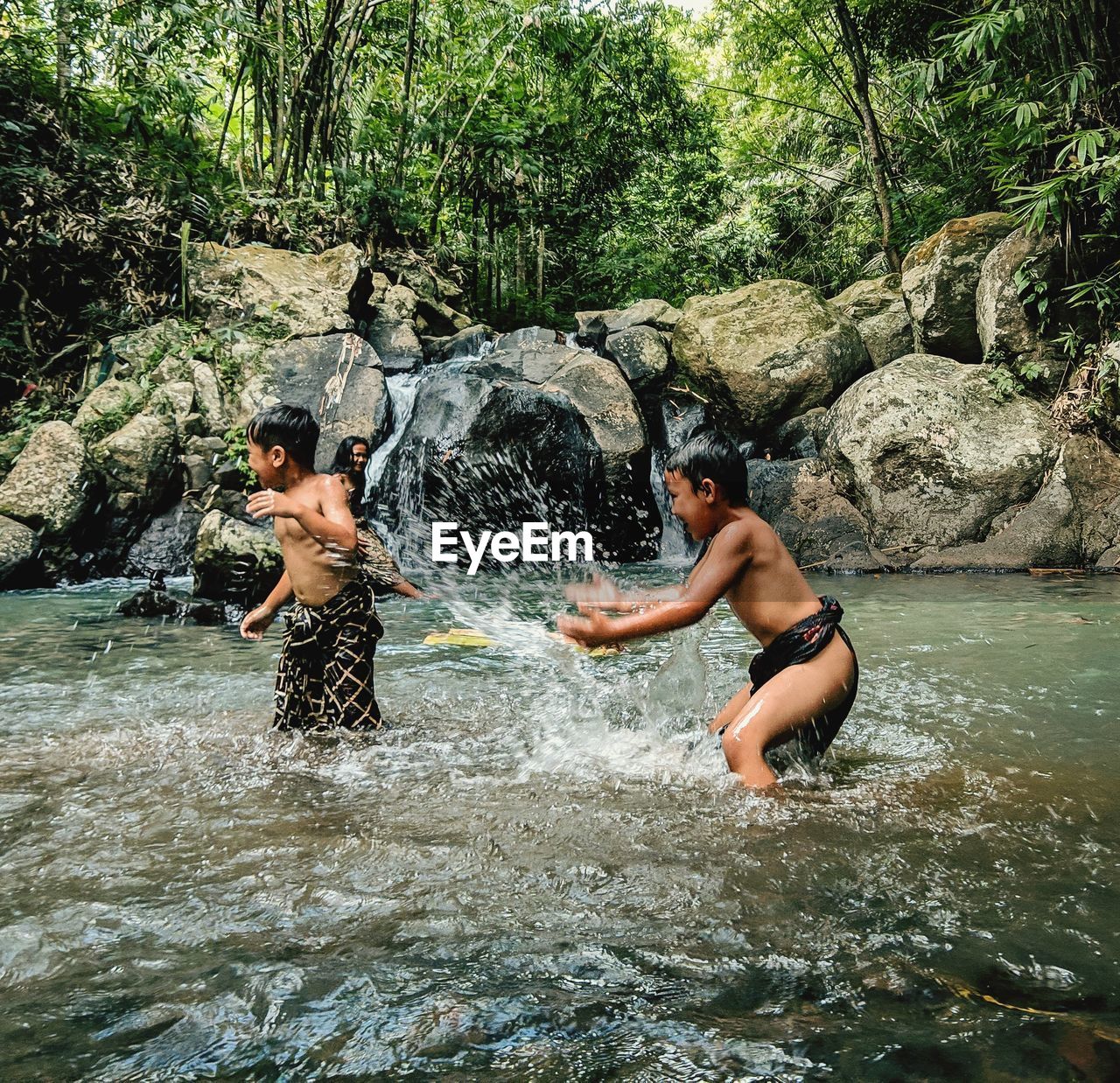 FULL LENGTH OF SHIRTLESS MAN SURFING ON ROCK