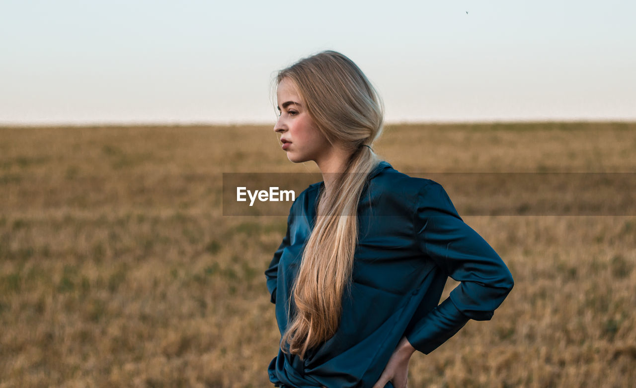 Woman looking away while standing on land against sky