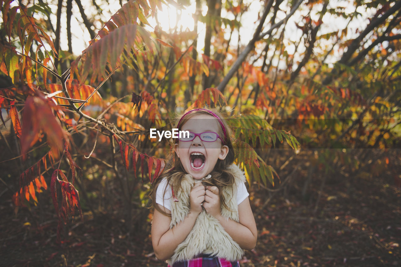 Cheerful girl with mouth open in front of plants during autumn