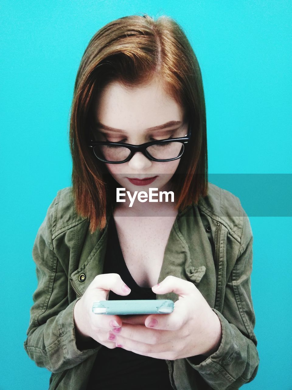 Teenage girl using mobile phone against blue background