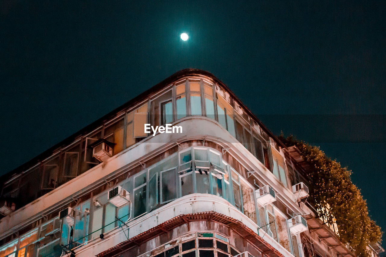 LOW ANGLE VIEW OF ILLUMINATED BUILDING AGAINST CLEAR SKY AT NIGHT