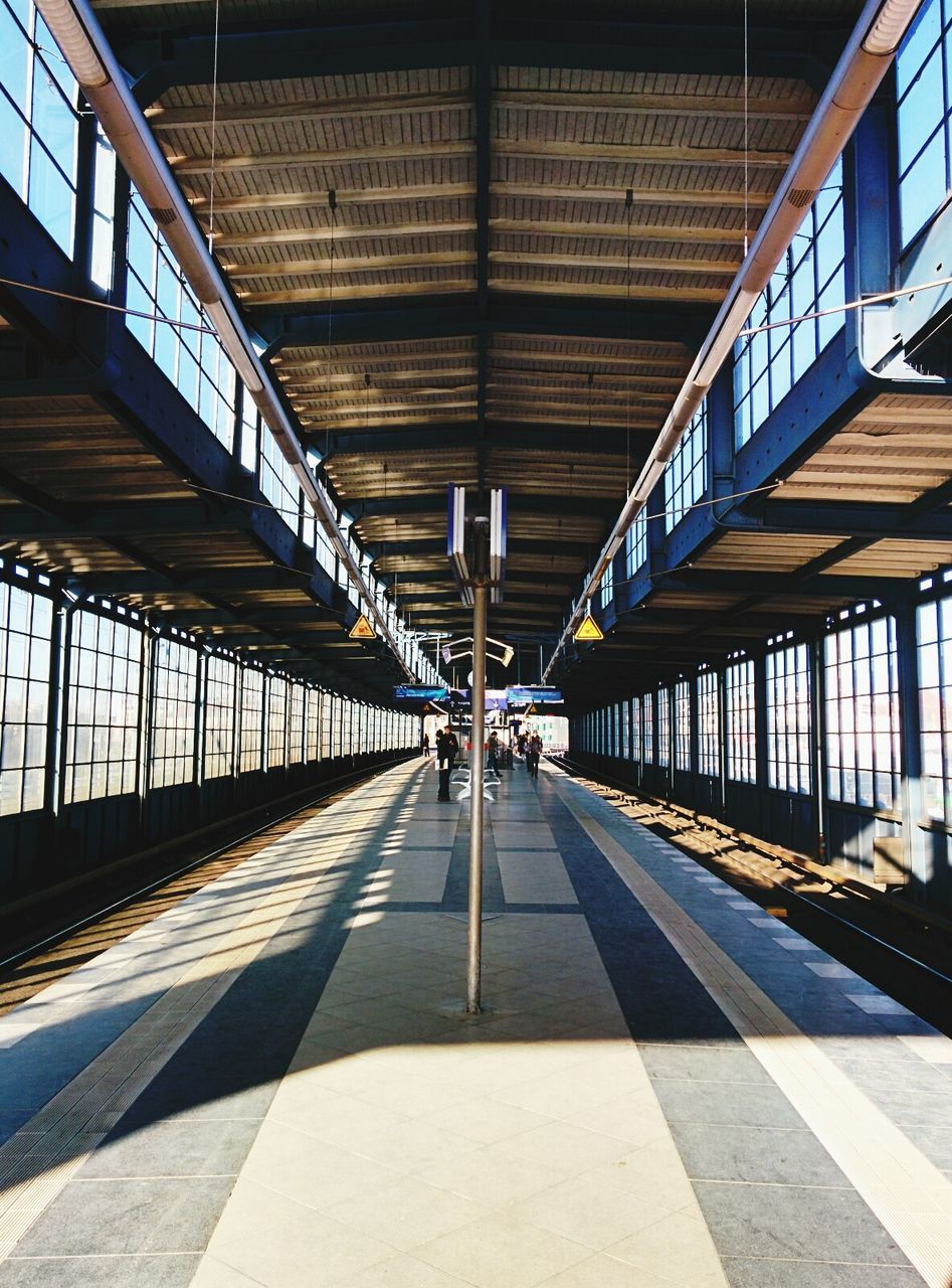 People waiting on roofed railway station platform