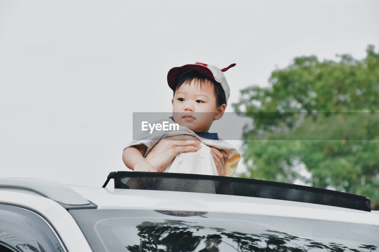 Boy looking away against car