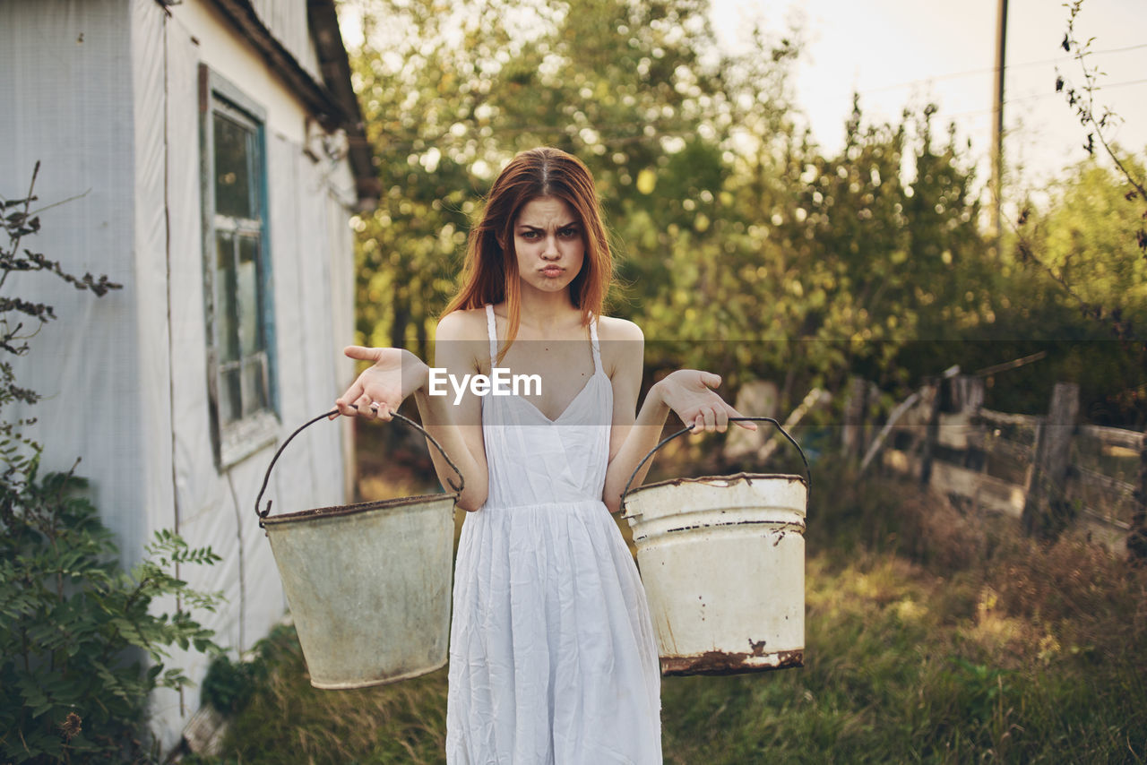 Portrait of smiling young woman standing against plants