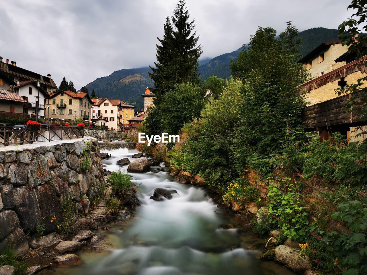 River amidst houses and buildings against sky