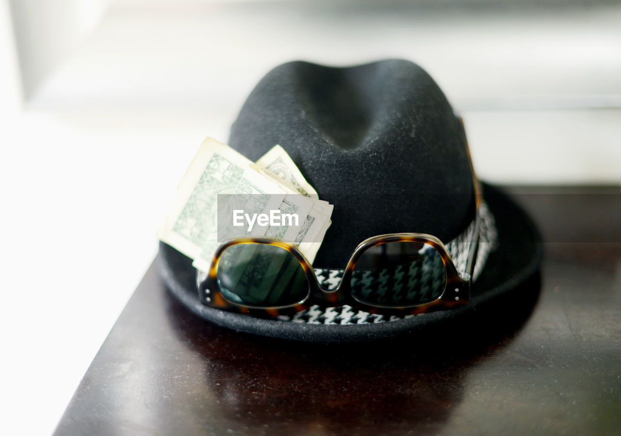 Close-up of hat with sun glasses and money