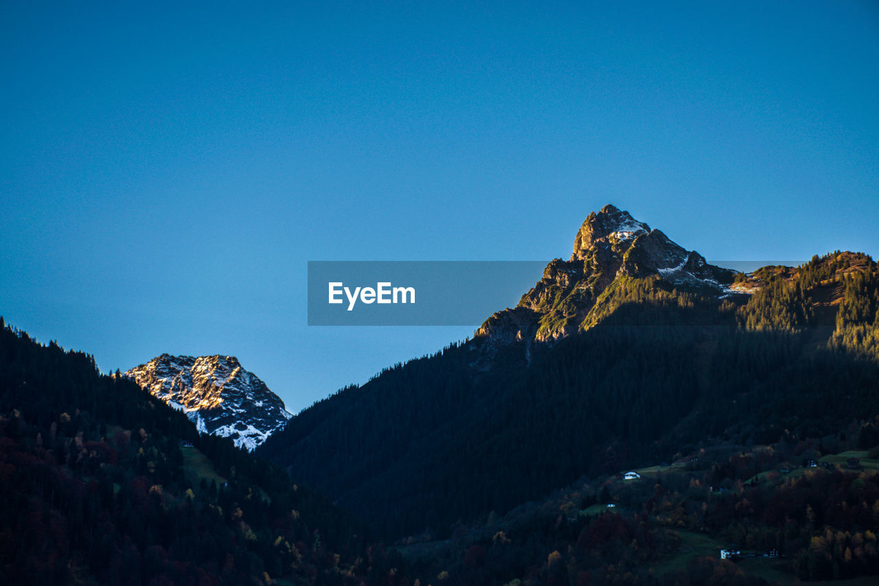 Low angle view of mountains against clear blue sky