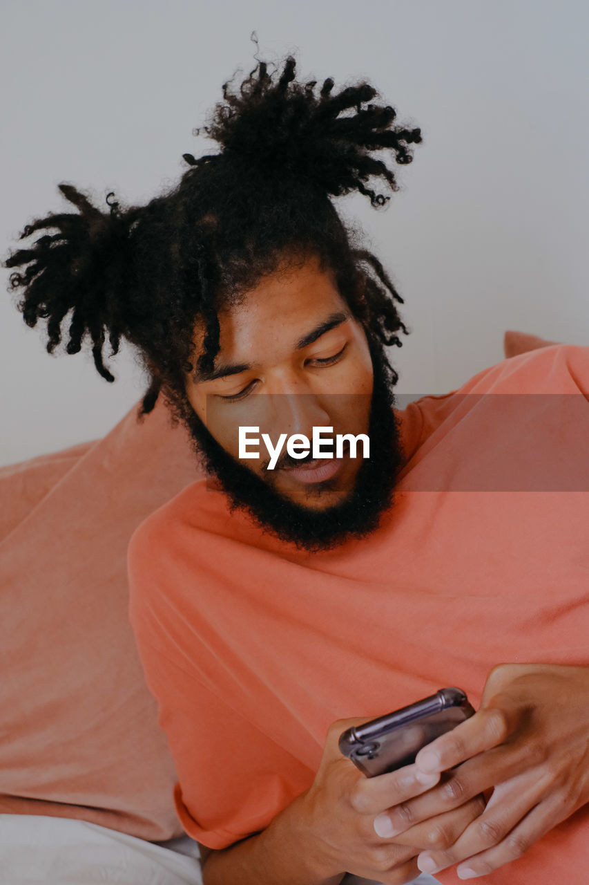 Young man using mobile phone while lying on bed