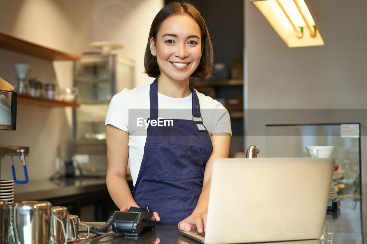 portrait of young woman using phone while sitting on table