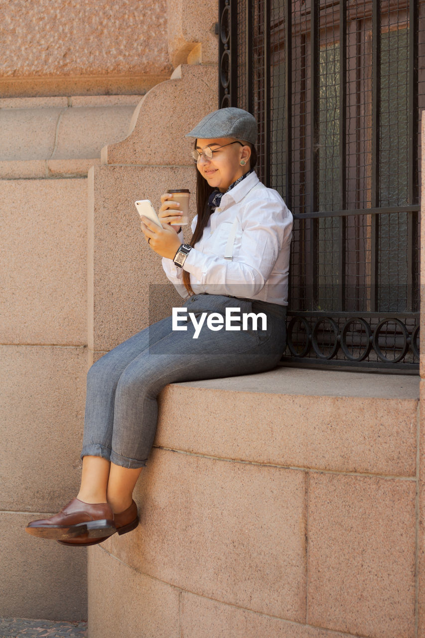 MIDSECTION OF WOMAN SITTING AGAINST WALL