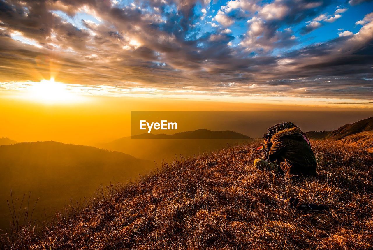 Hiker sitting on mountain during sunset