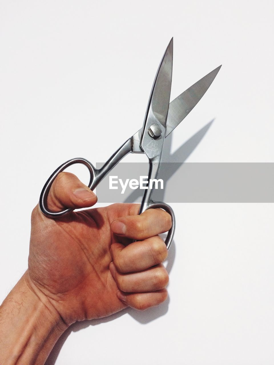 Cropped image of man holding silver scissors over white background