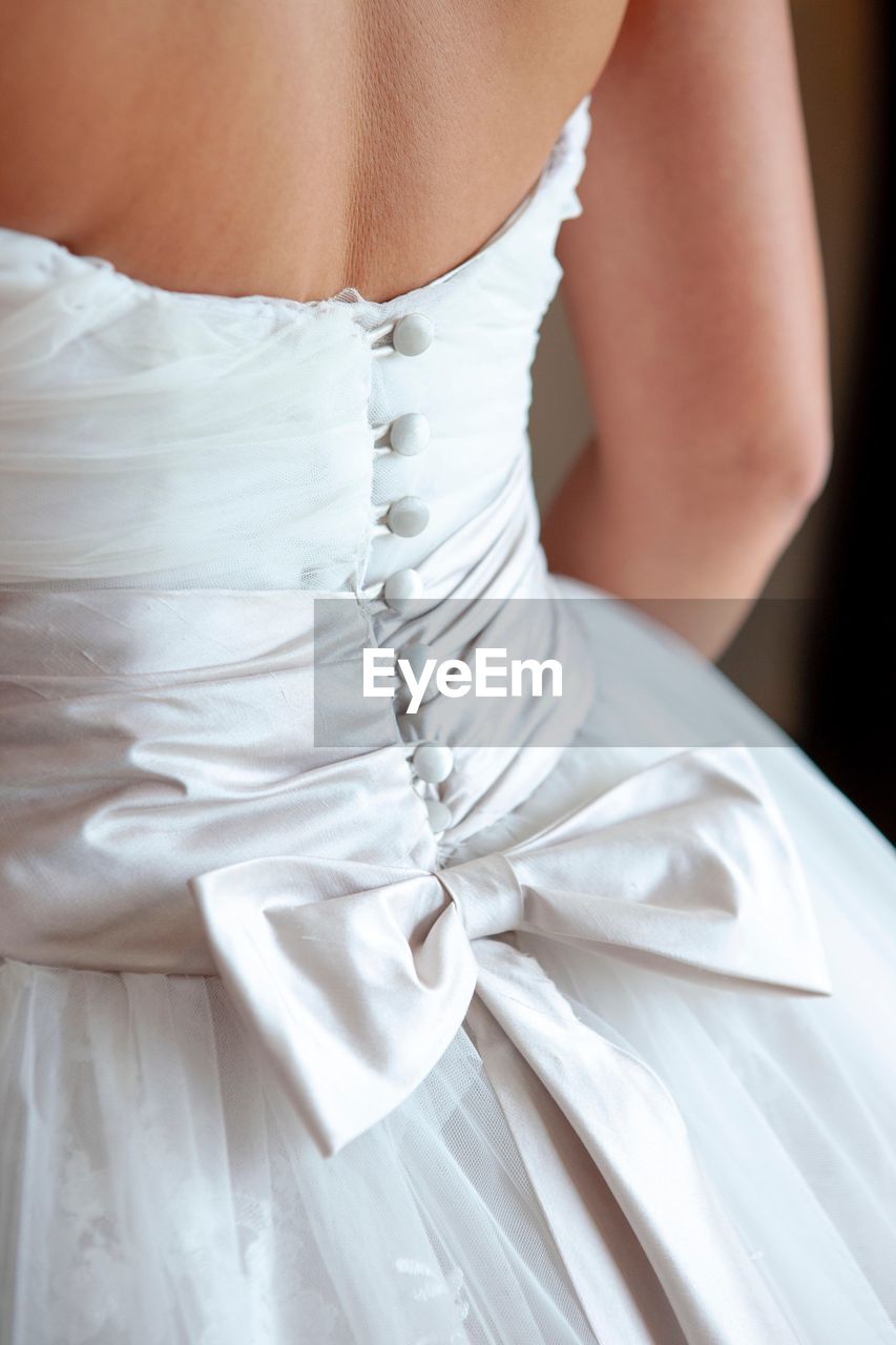 Midsection of bride wearing wedding dress