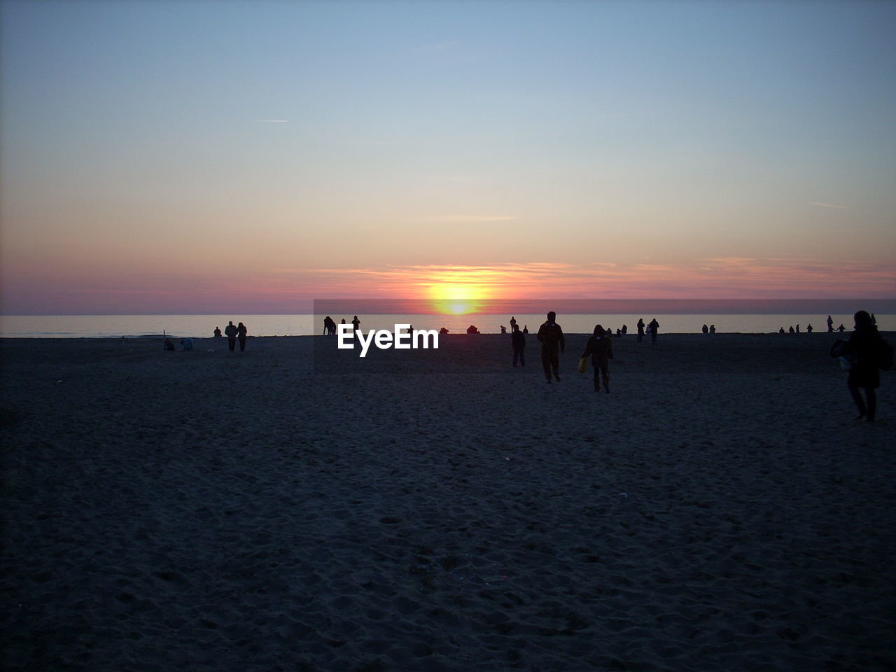 Silhouette people at beach against sky during sunset