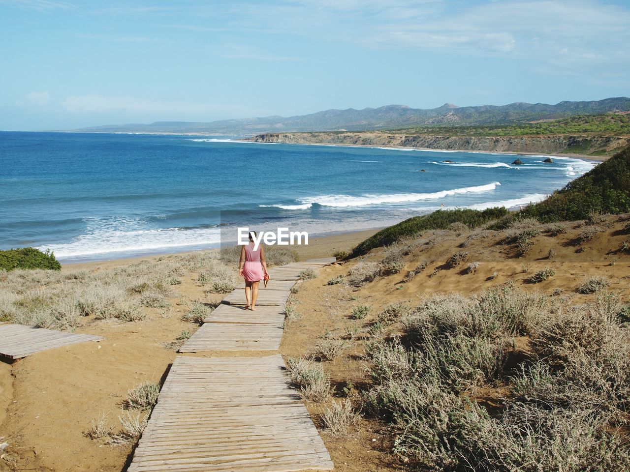 Rear view of a woman walking on pathway at beach