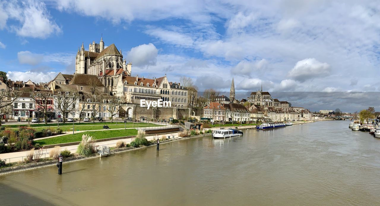 View of church by river against cloudy sky