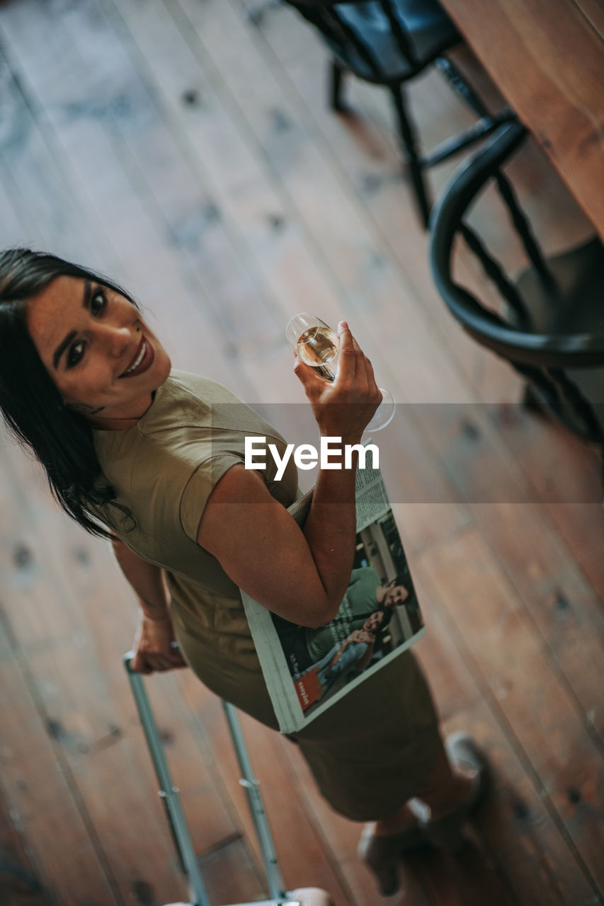 Woman reading magazine while having wine at home