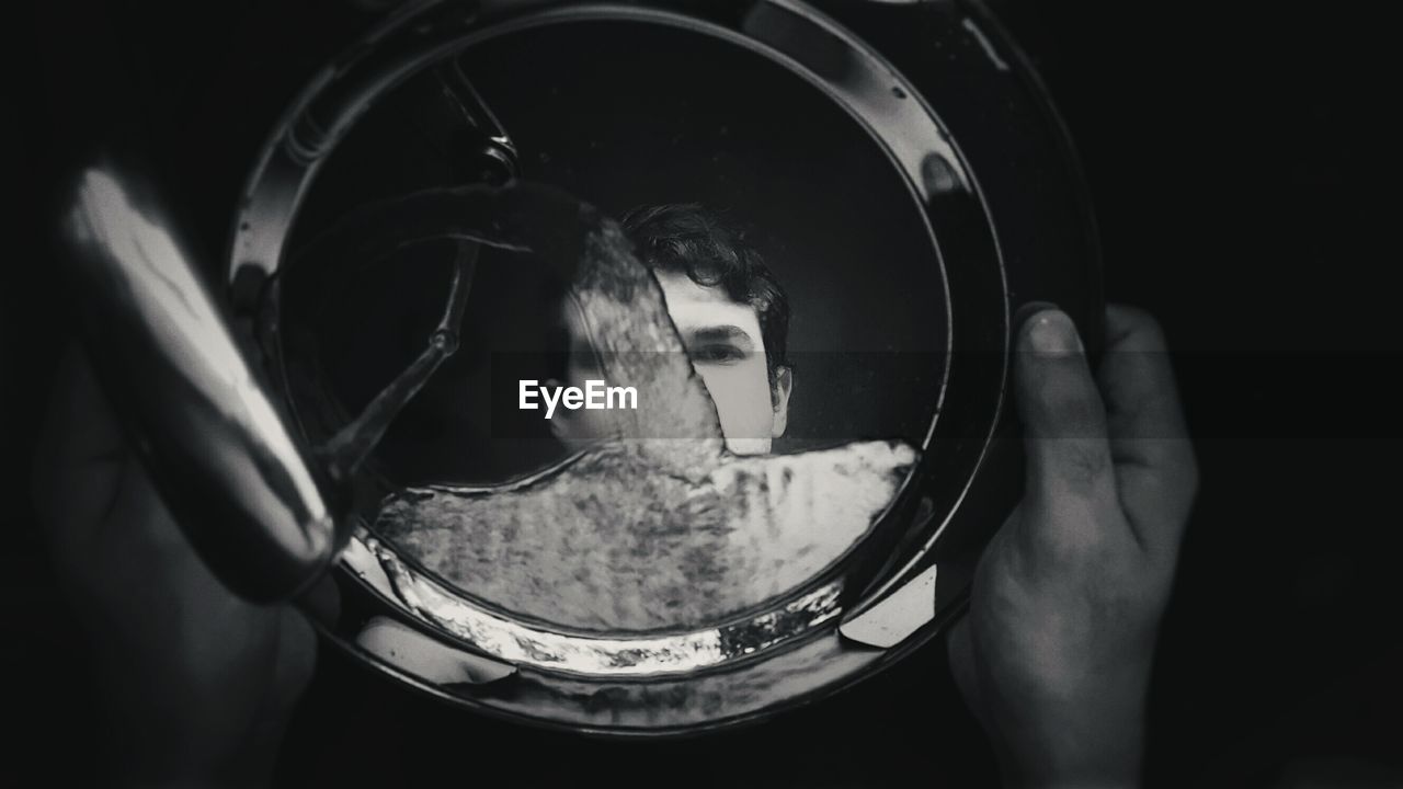 Cropped hand of man washing plate with reflection