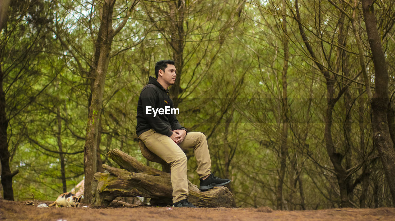 Full length of young man sitting in forest