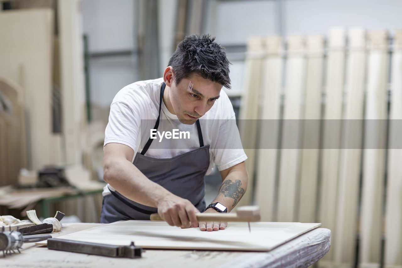 Artist giving design to wood through traditional method while standing at workshop