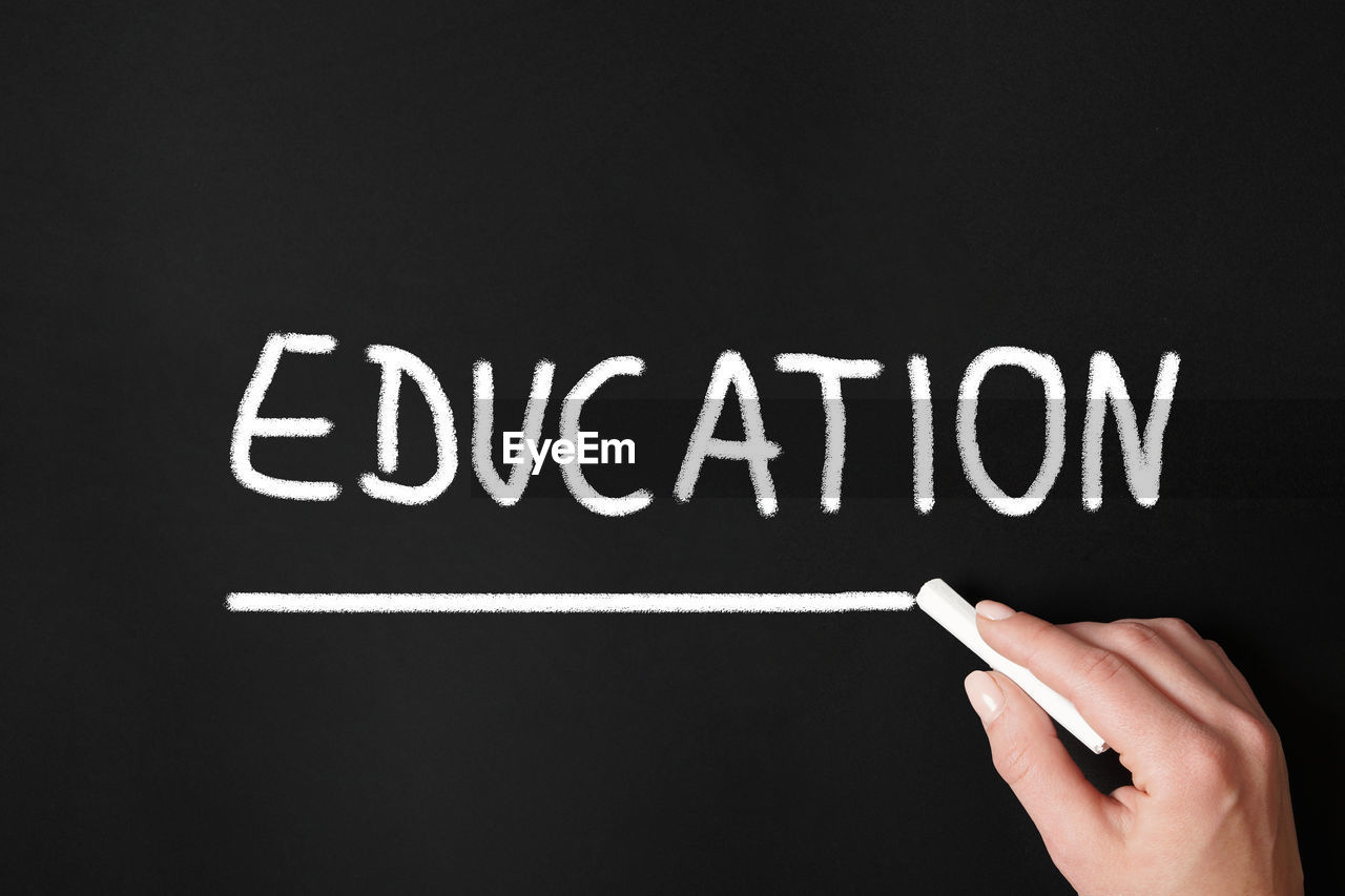 Close-up of hand writing education on blackboard
