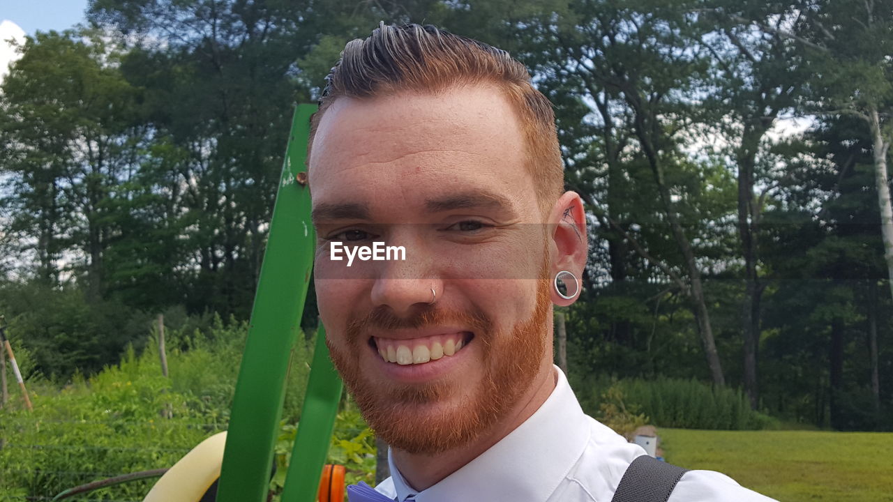 Close-up portrait of smiling young man standing at park