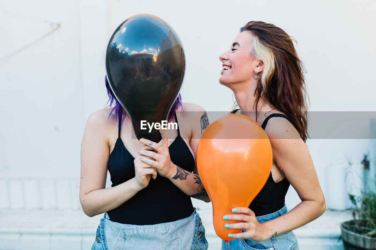 Lesbian women holding balloon while standing outdoors