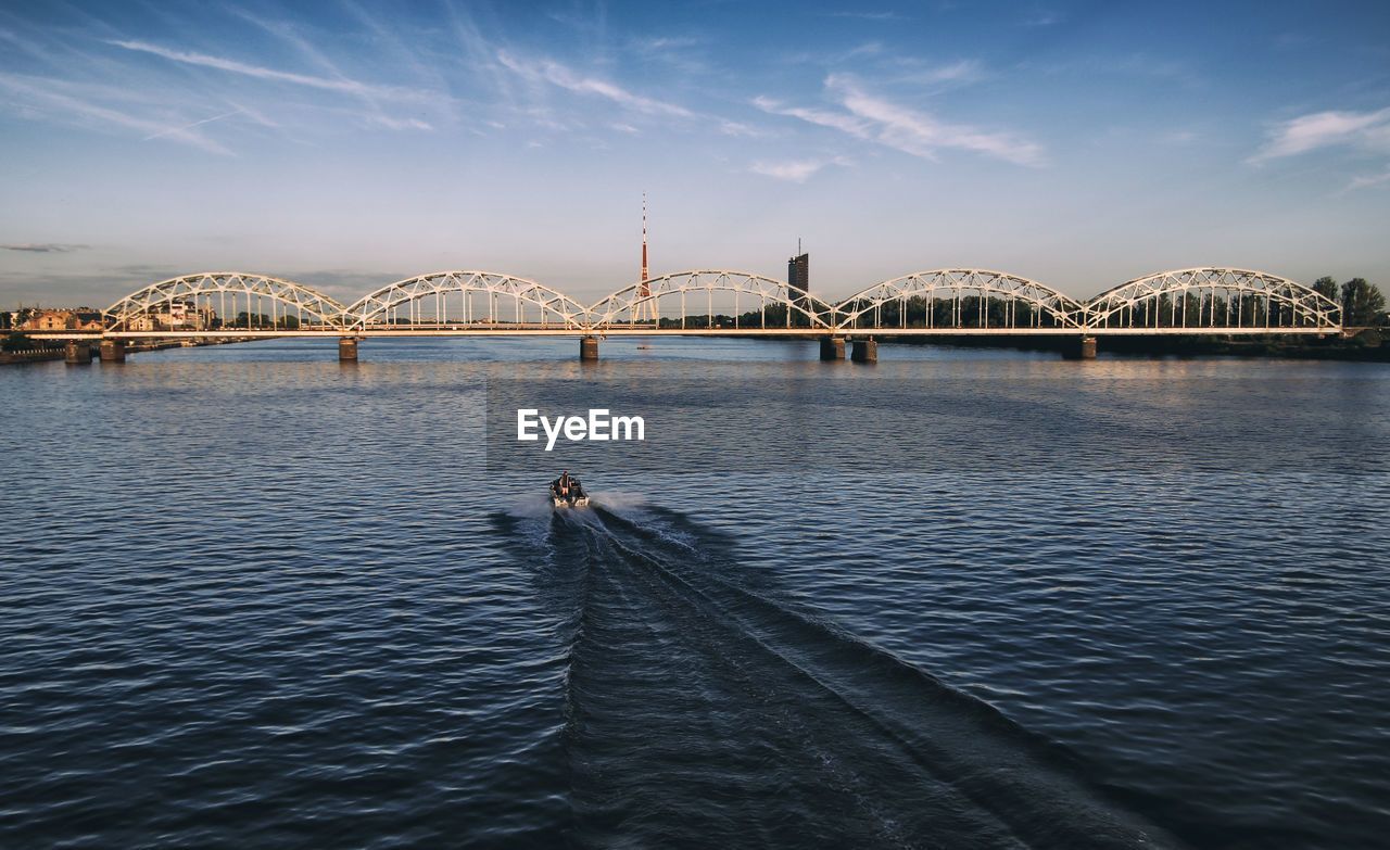 Bridge over river in city against sky