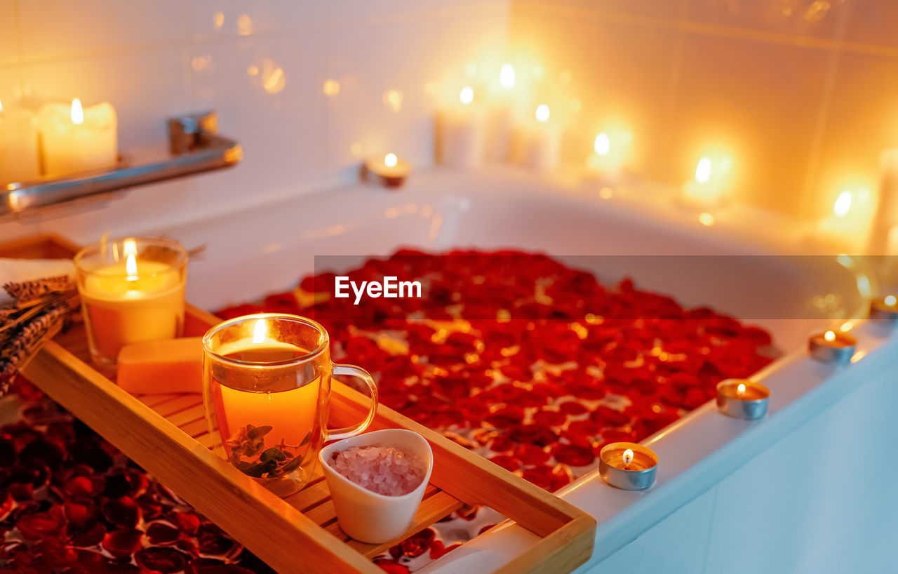 Herbal mint tea on bathtub tray with candles, lavender and salt during spiritual aura cleansing 