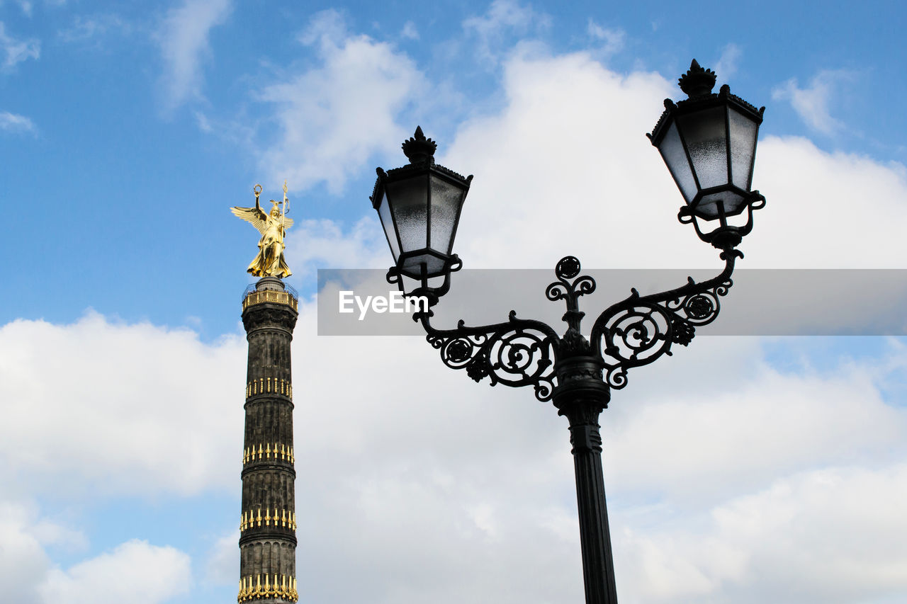Low angle view of antique street light with berlin victory column against sky