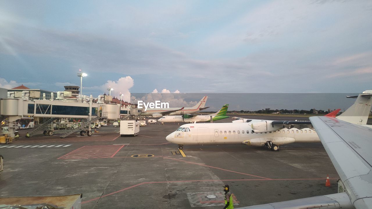 transportation, airplane, air vehicle, mode of transportation, airport, infrastructure, airport runway, vehicle, travel, aviation, aircraft, sky, nature, tarmac, airport apron, cloud, business, road, industry, architecture, loading, aerospace industry, day, airliner, outdoors, business finance and industry, freight transportation, asphalt, jet bridge, air force
