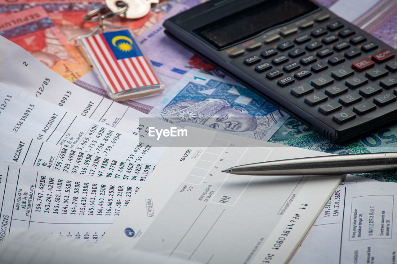 High angle view of pen on paper with malaysian ringgit currency and calculator. 
