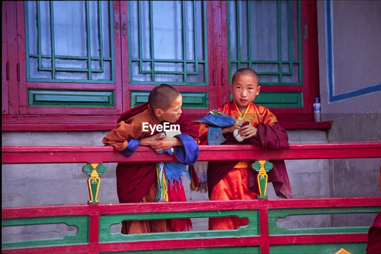 FULL LENGTH OF A SMILING BOY SITTING ON A TRADITIONAL CLOTHING