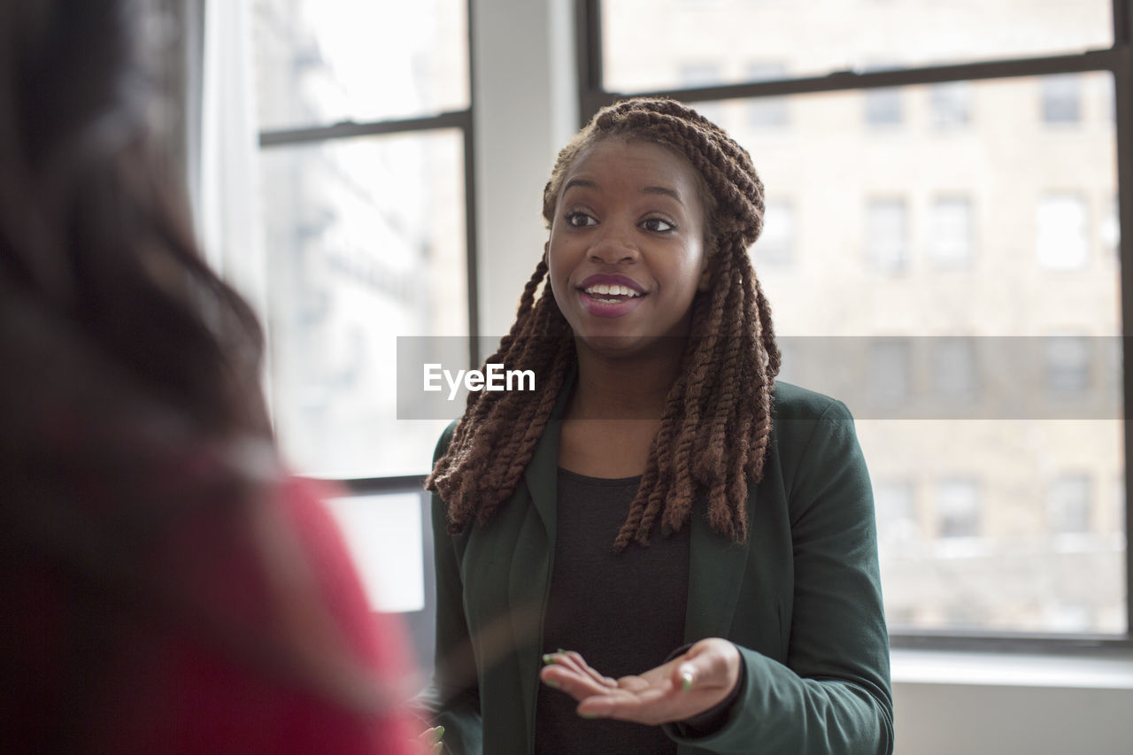 Businesswoman talking to colleague while standing in office