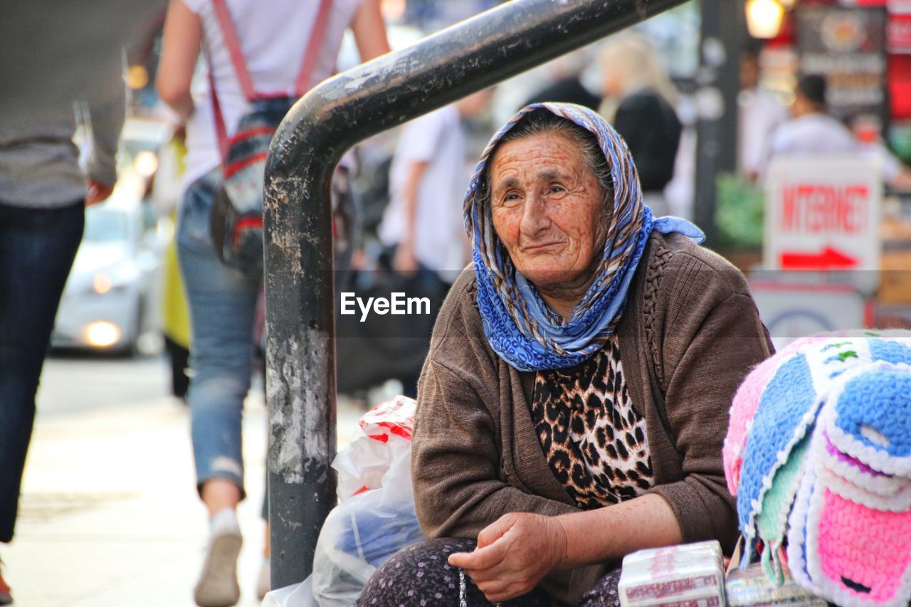Senior woman looking away while sitting on street