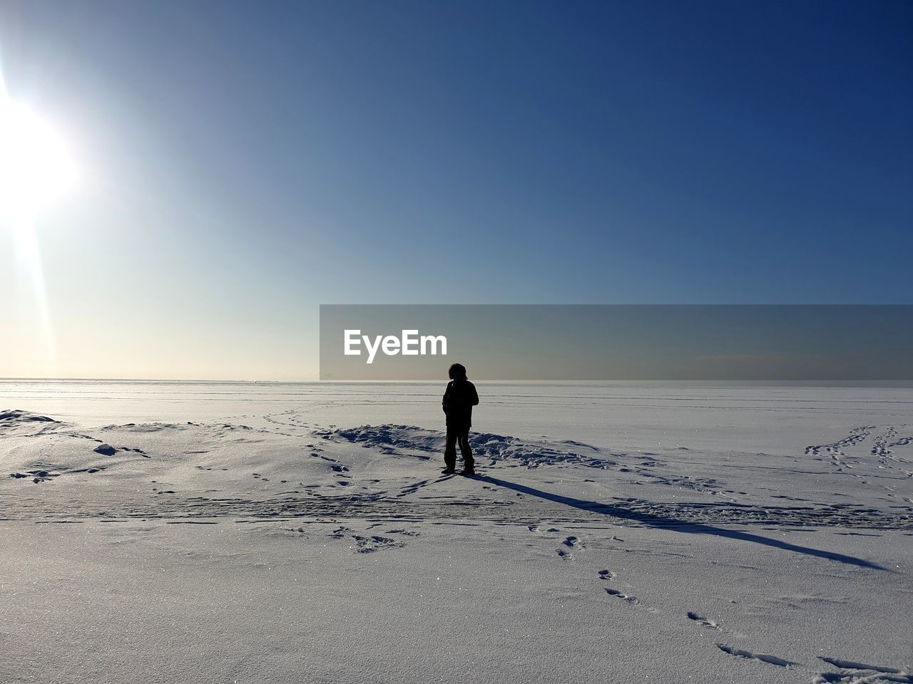 REAR VIEW OF PERSON STANDING ON BEACH DURING WINTER