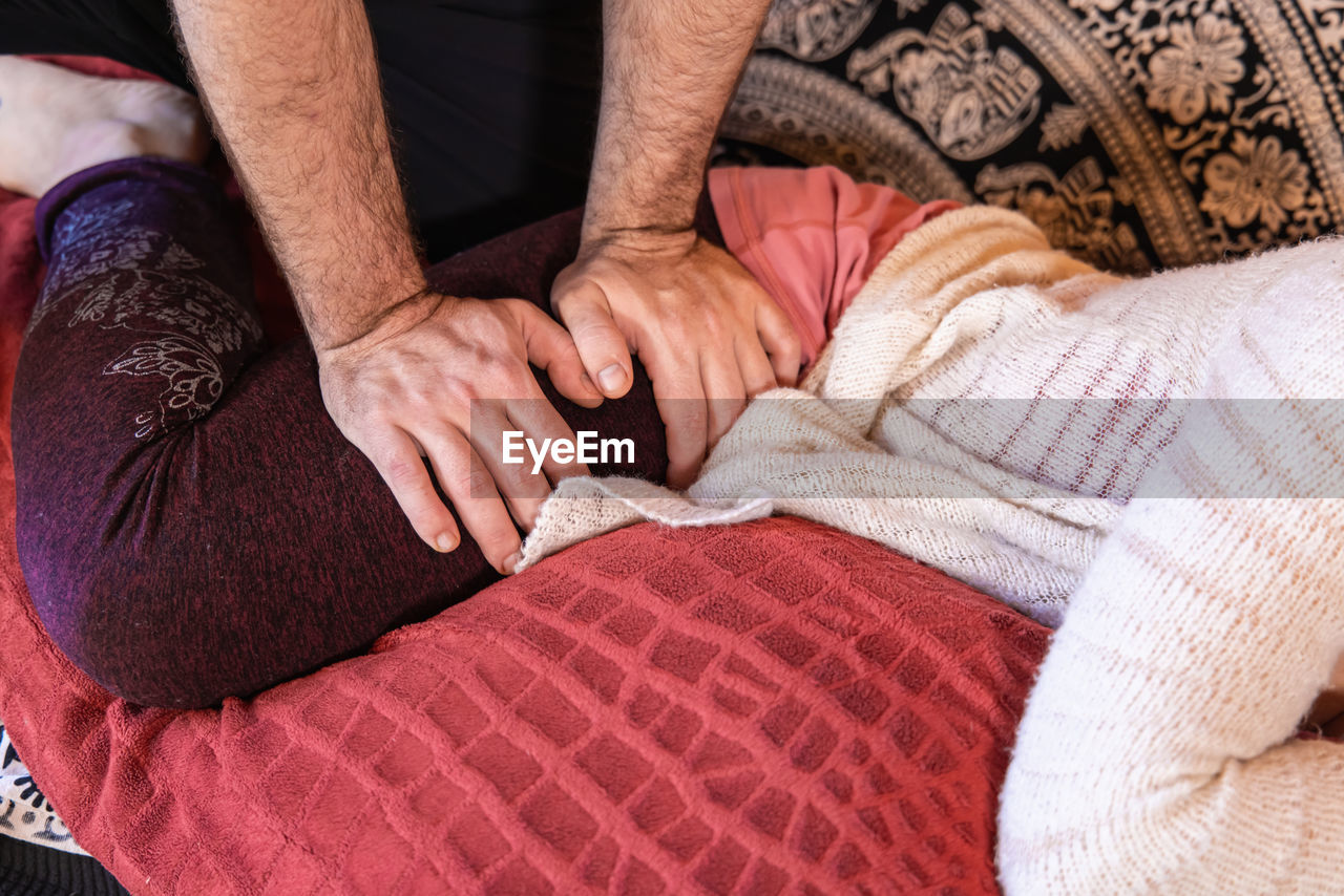 low section of woman sitting on bed at home