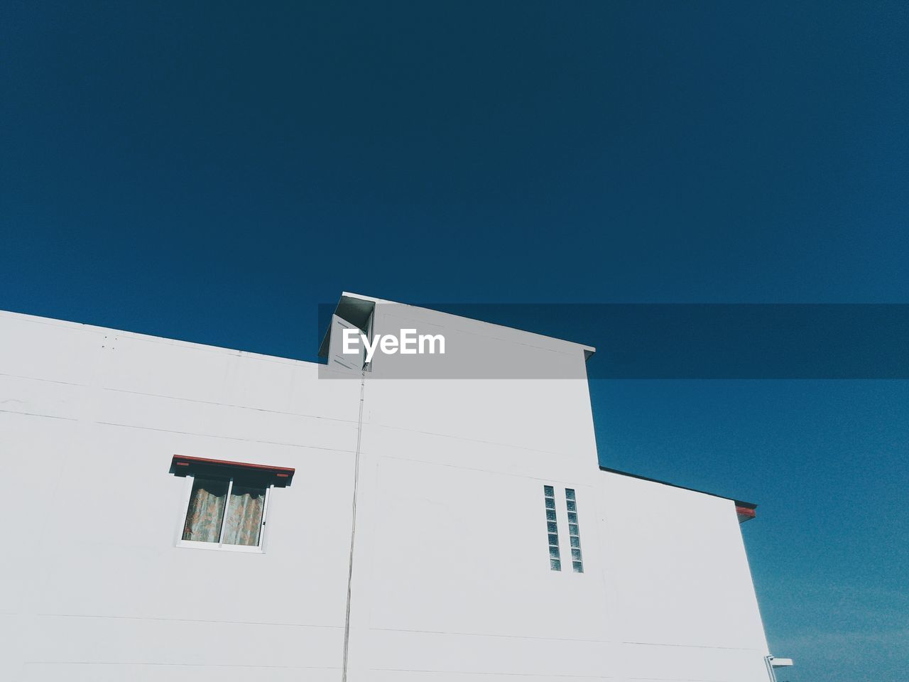 LOW ANGLE VIEW OF WHITE BUILDING AGAINST CLEAR BLUE SKY