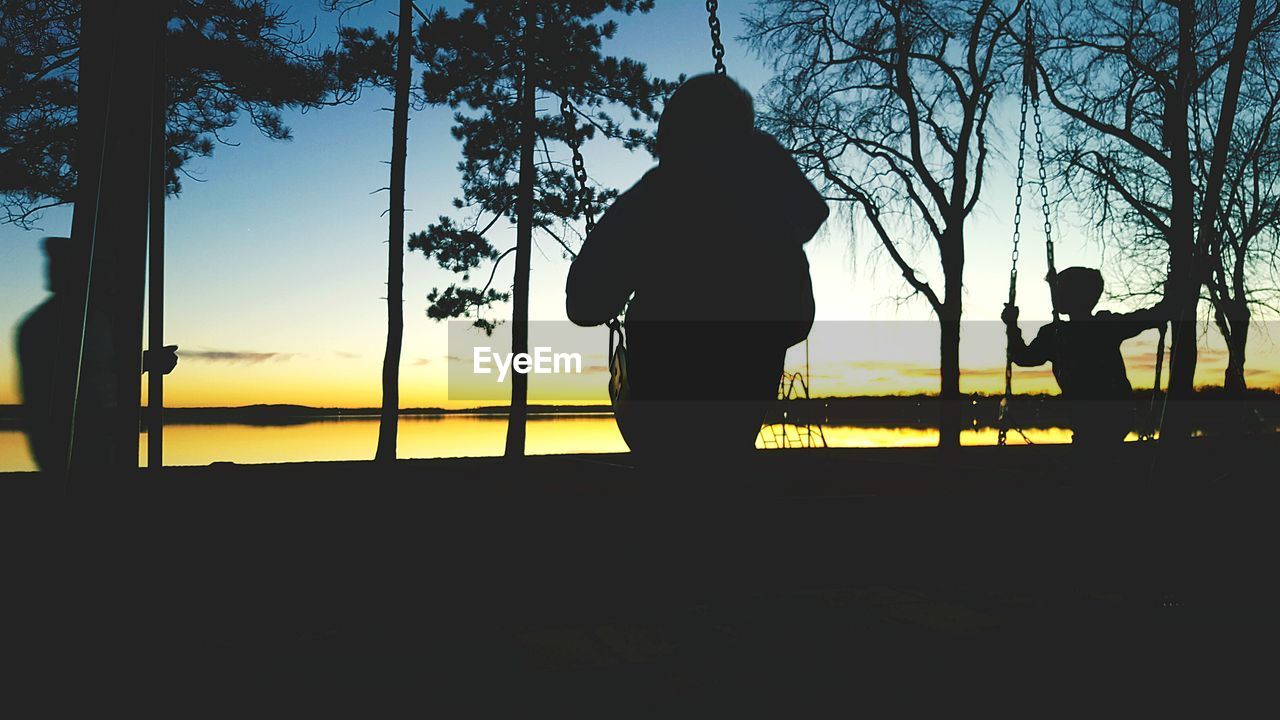 REAR VIEW OF SILHOUETTE MAN STANDING AGAINST TREES