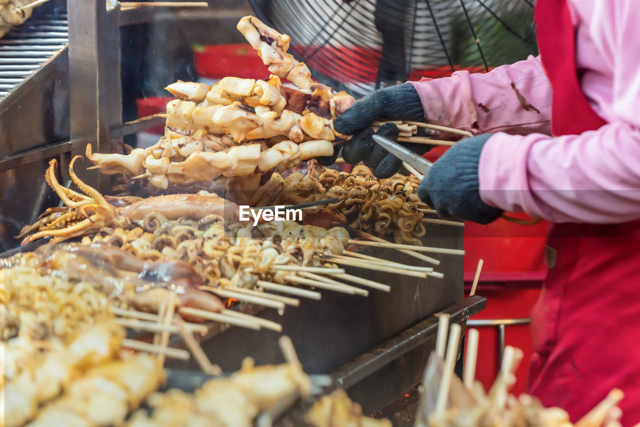 midsection of person preparing food on barbecue grill