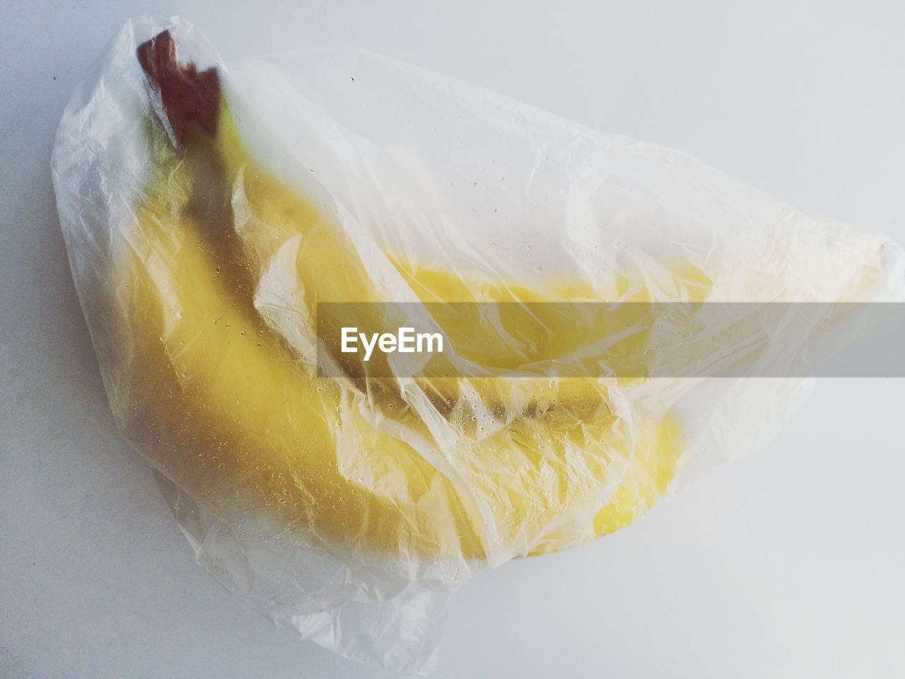 High angle view of bananas in plastic on white table