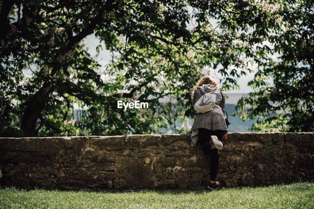 Woman standing by tree against sky