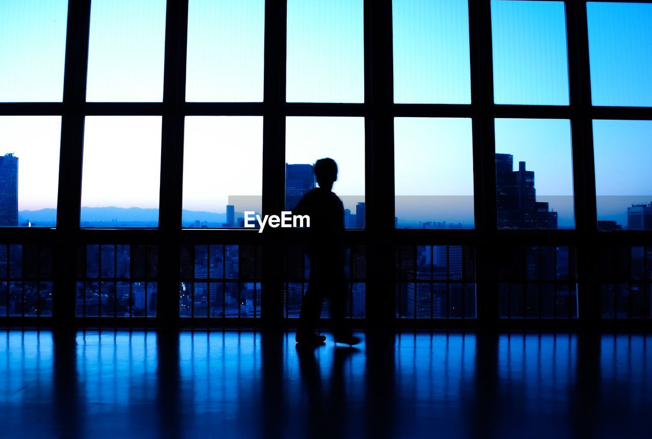SILHOUETTE MAN STANDING AT WINDOW OF BUILDING