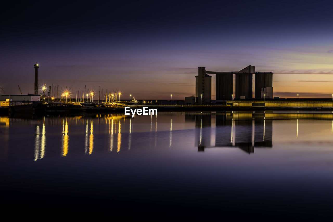 Reflection of illuminated bridge over river at sunset