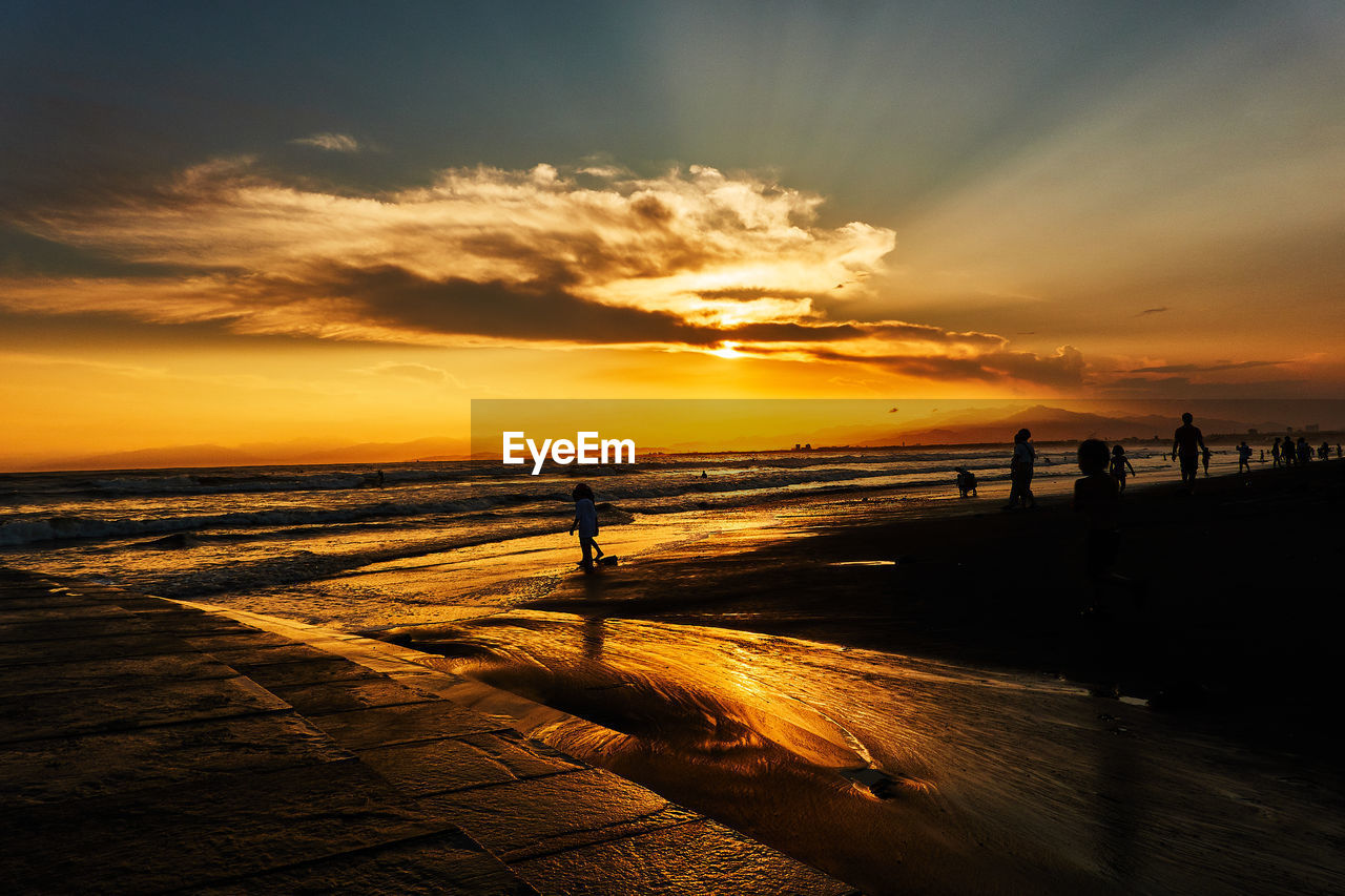 Silhouette person on beach against sky during sunset