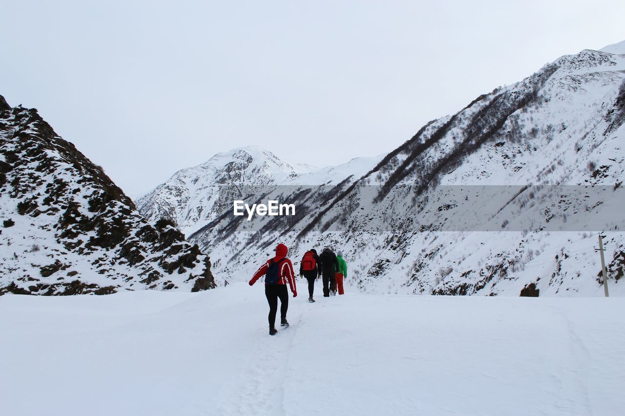 People walking on snow against snowcapped mountains